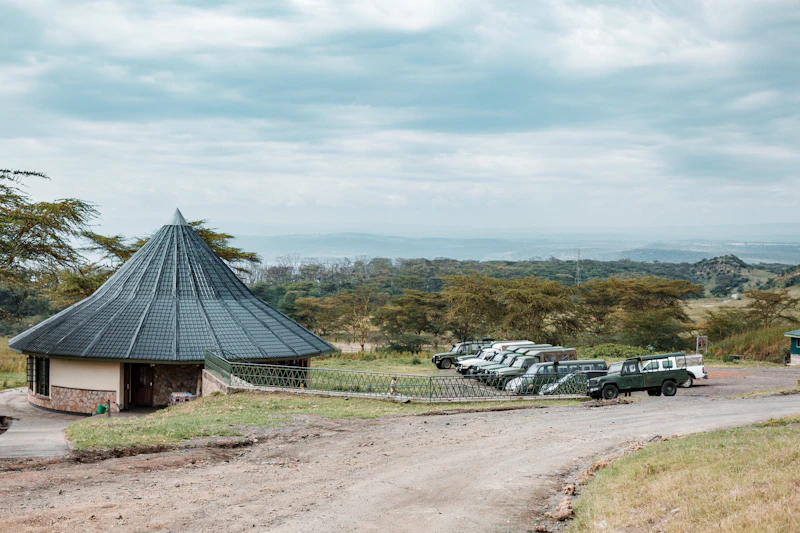 Safari camp and vehicles parked in front of scenic hill country
