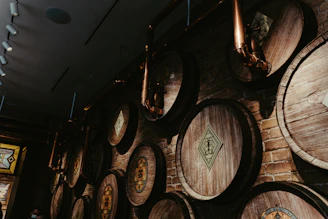 Photograph of a seasoned distiller inspecting copper pot stills in a dimly lit, professional distillery.