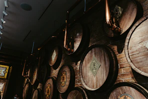 An atmospheric view of a shadowed distillery room with copper stills glowing softly under low light.