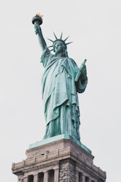 a statue of a person holding a torch with Statue of Liberty in the background