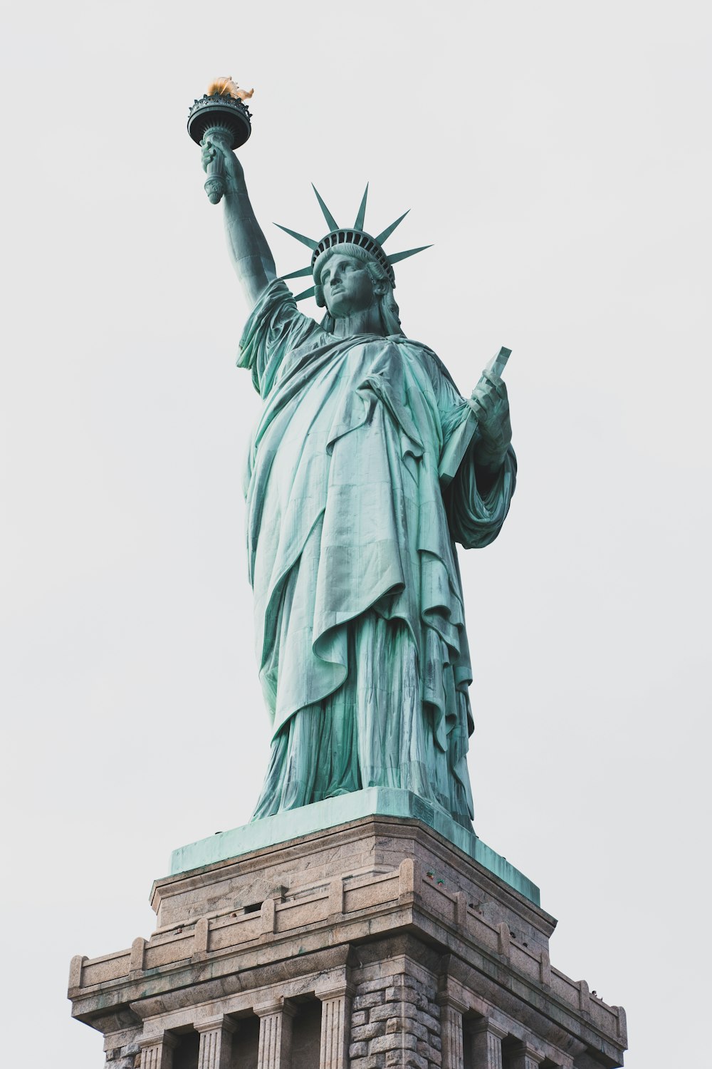 a statue of a person holding a torch with Statue of Liberty in the background