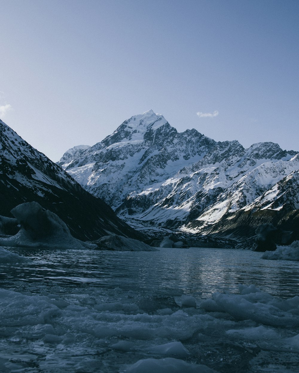 a body of water with snow covered mountains in the background