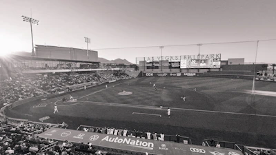A banner featuring sponsor logos hanging along the outfield fence during a sunny game day.