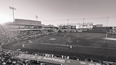 A baseball batter swinging hard as the ball approaches in a sunny stadium.