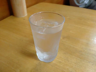 A clear, refreshing glass of ozonated alkaline water with ice cubes on a wooden table.