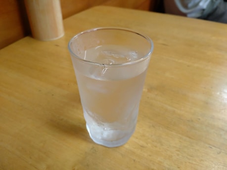 A close-up of a clear glass filled with pure water on a wooden table.