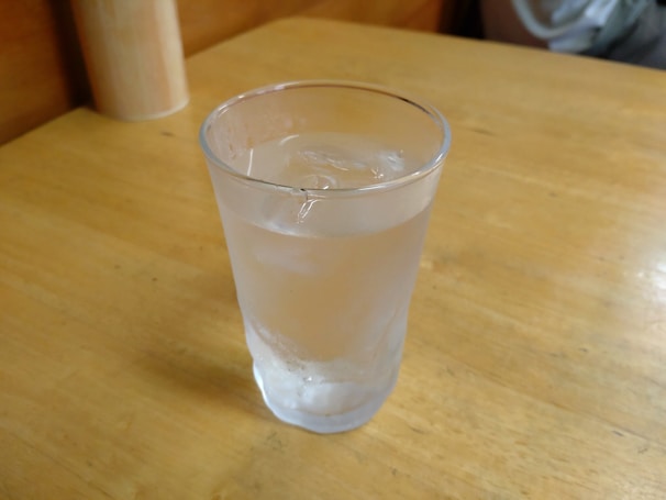 Clear glass filled with sparkling filtered water placed on a wooden kitchen counter.