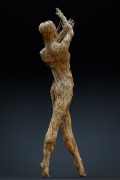 A sculpture formed by a network of intertwined wires is depicted, resembling a human figure in a dynamic, expressive pose with raised arms. The intricate structure gives an impression of movement and grace while remaining grounded.