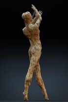 A sculpture formed by a network of intertwined wires is depicted, resembling a human figure in a dynamic, expressive pose with raised arms. The intricate structure gives an impression of movement and grace while remaining grounded.