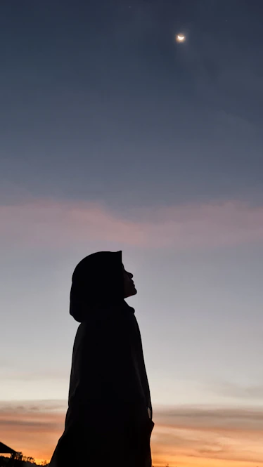 a silhouette of a woman and a man in front of a sunset