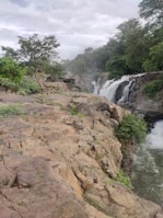 a rocky cliff with trees and a waterfall