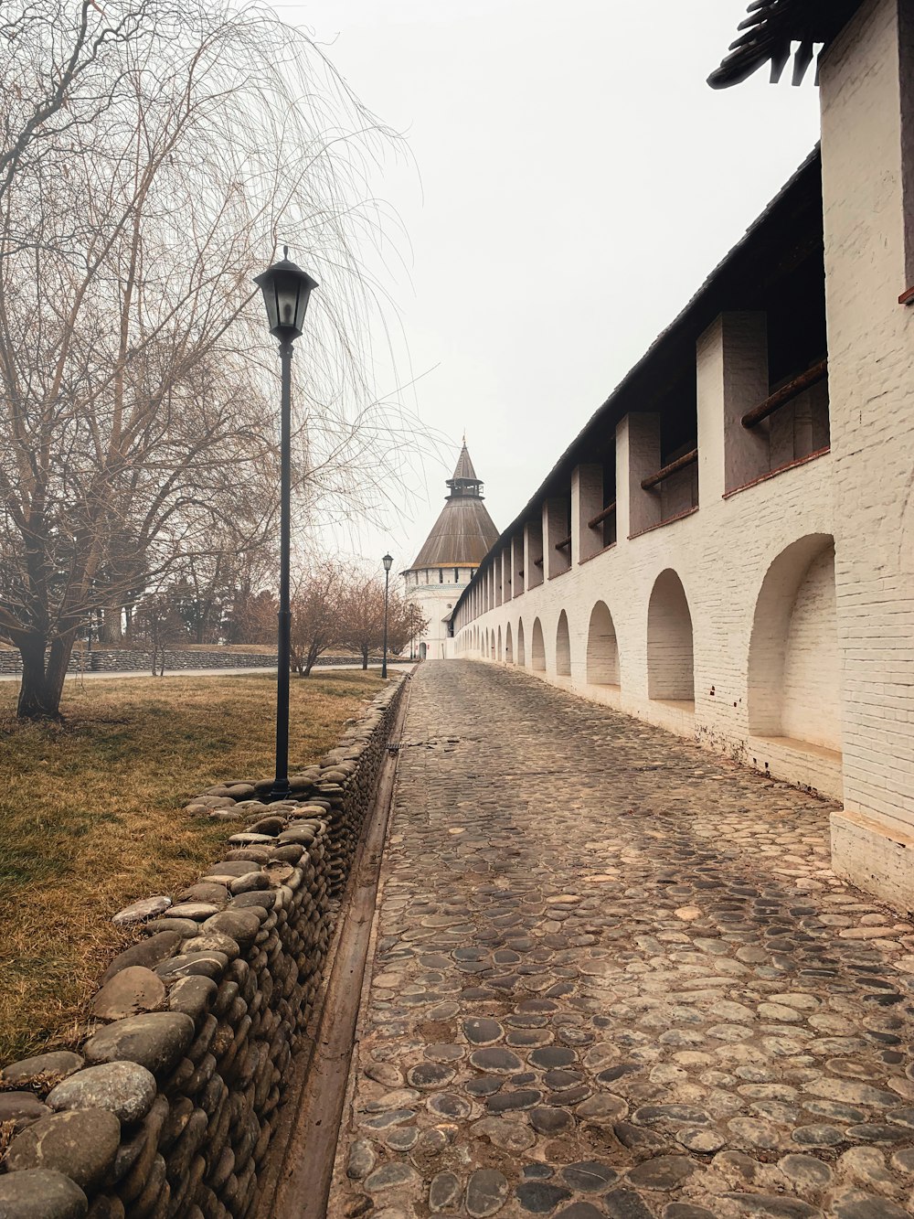 a stone path with a stone wall and a building on the side