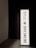 A vertically oriented lightbox displays the text 'DREAMS HAVE NO TITLES' in bold, black uppercase letters on a white background. The lightbox is positioned in a dimly lit space, creating a stark contrast between the illuminated sign and the dark surroundings.