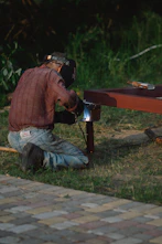 a person squatting down next to a red table