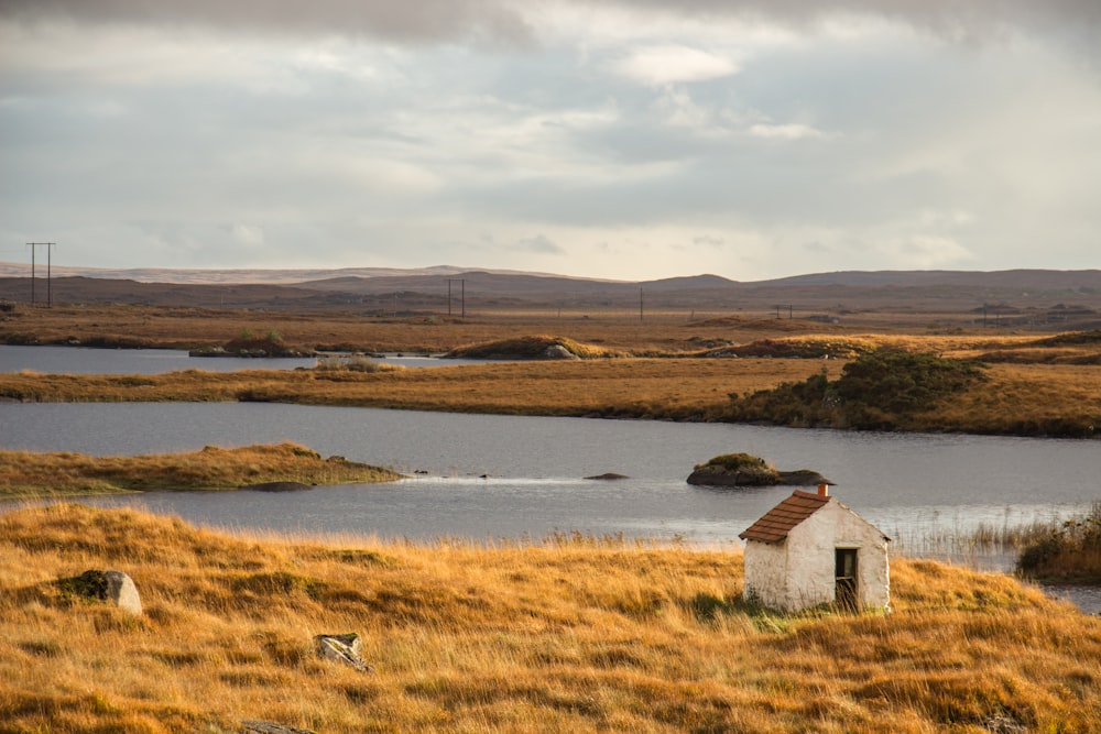 a small white building next to a body of water