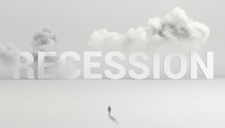 Large letters spelling 'RECESSION' are positioned above a flat, fog-covered landscape. A solitary figure stands below the letters, dwarfed by their size. Billowing clouds of smoke or fog provide a dramatic backdrop, accentuating the sense of isolation.
