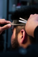 Beard trimming session showing careful shaping with scissors and comb.