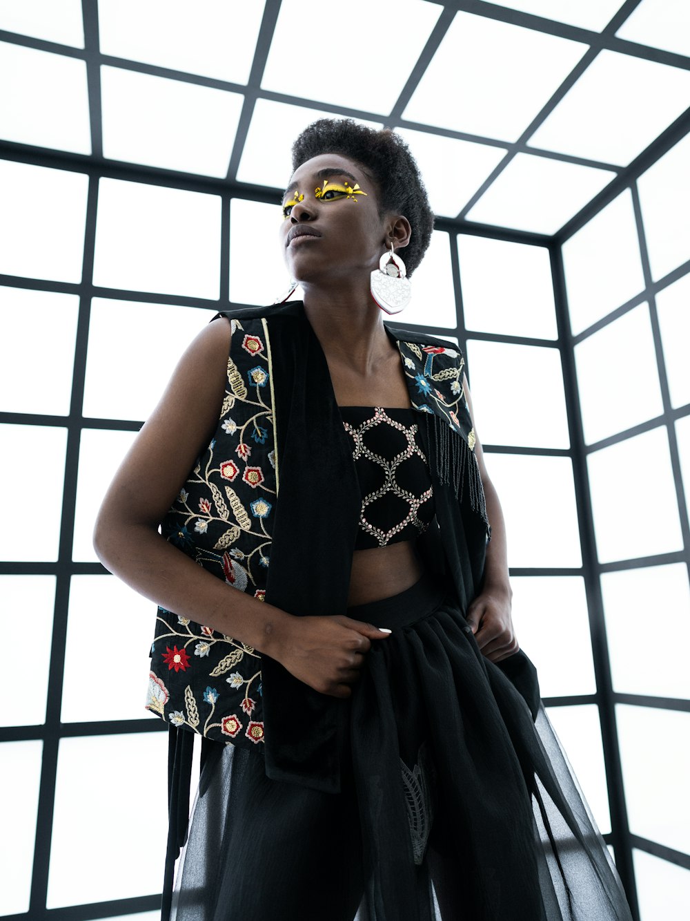 a woman with a black dress and yellow sunglasses with a black and white background