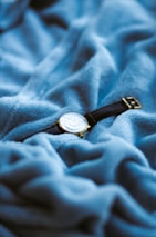 Nichelle LLC watch resting elegantly on a soft fabric background, highlighting its stainless steel strap.