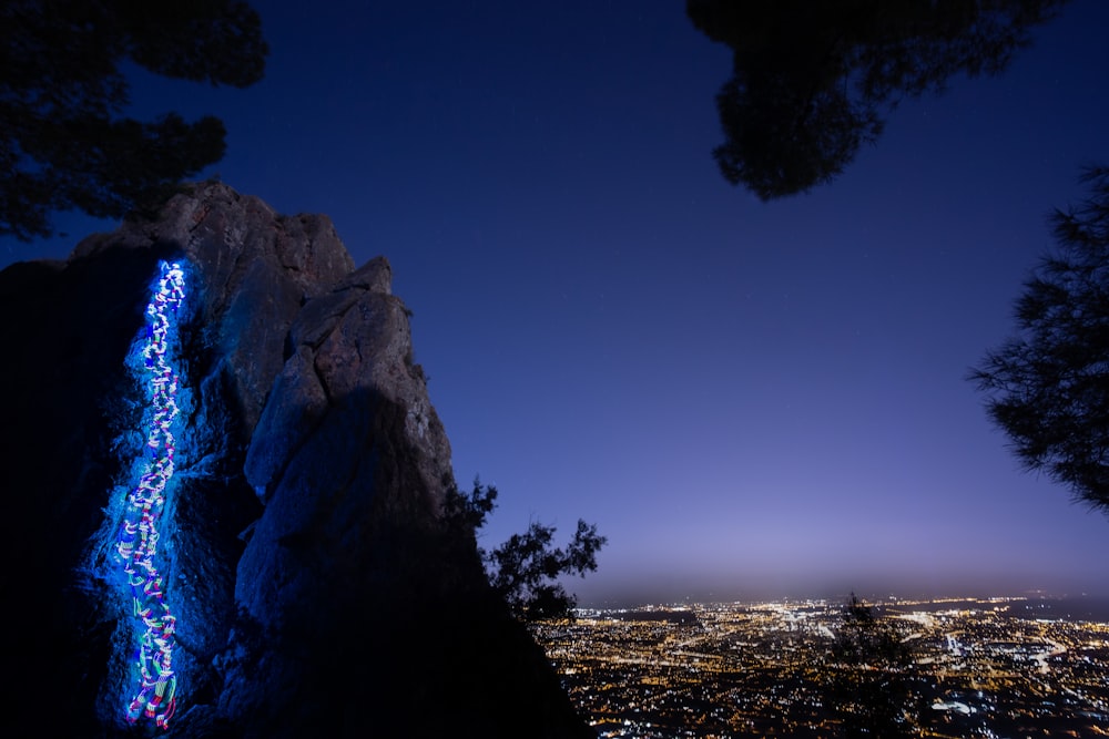 a large rock formation with a city below at night