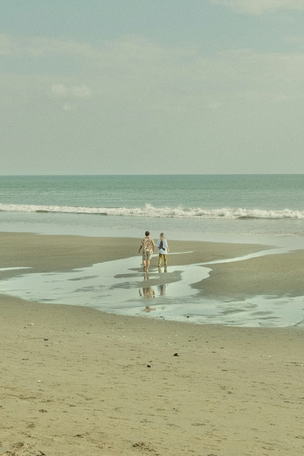 a person standing on top of a sandy beach next to the ocean