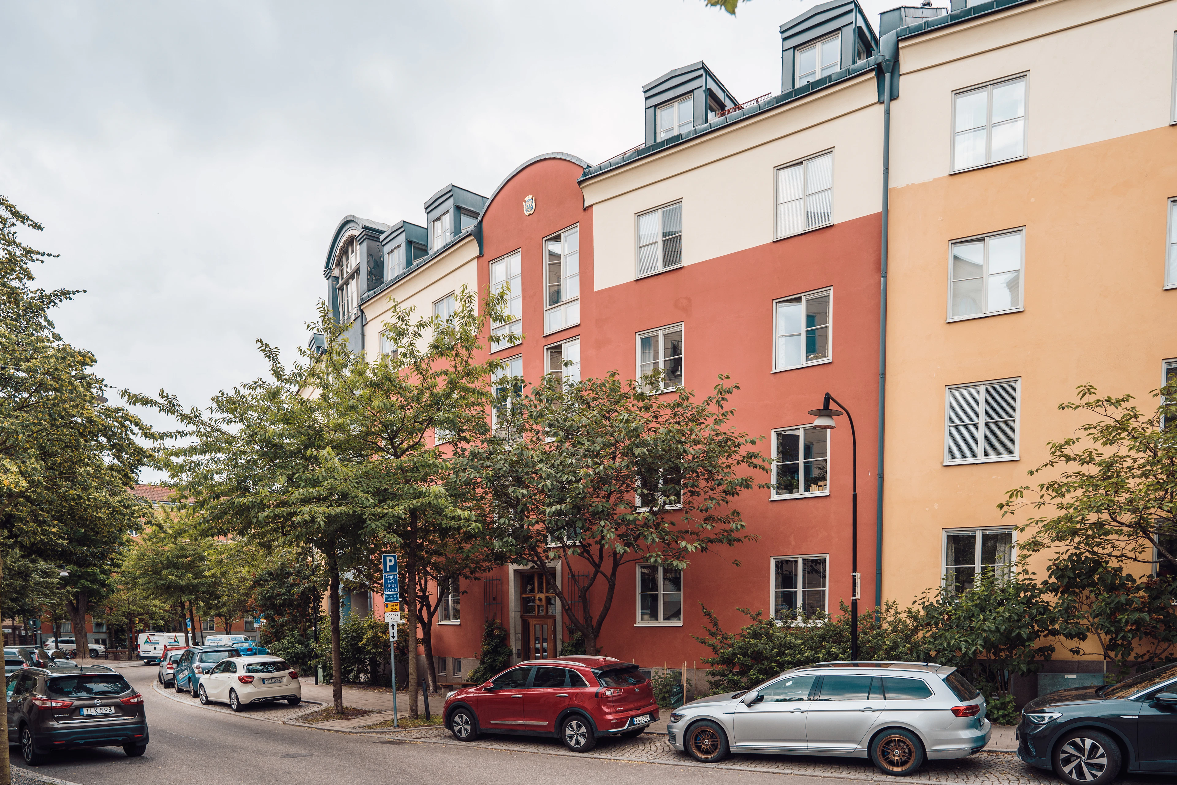 Gata med parkerade bilar framför hyreshus i Stockholm