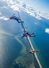 Skydiver in mid-air above a sparkling ocean coastline