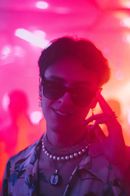 A model wearing layered necklaces and matching earrings in a sunlit room.