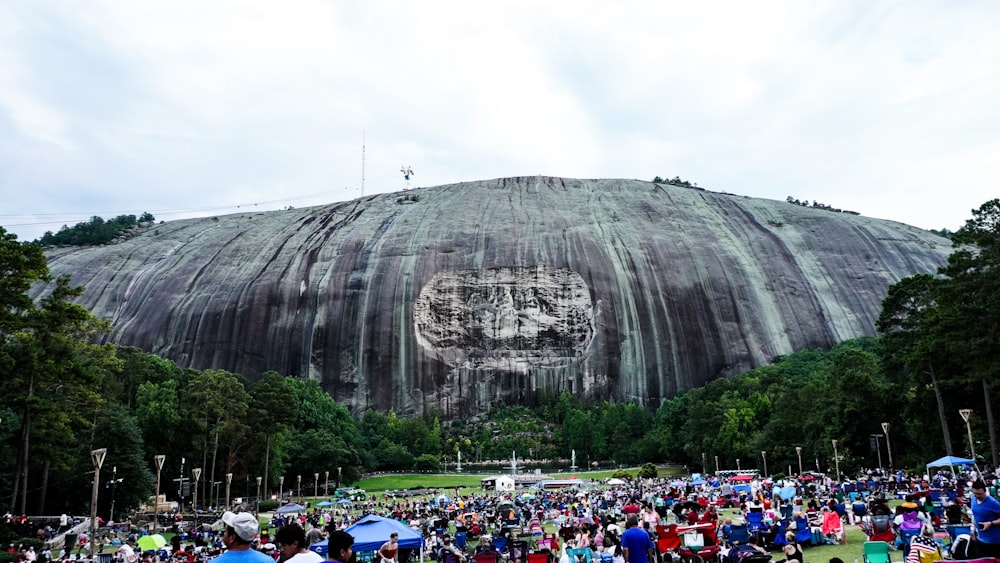 a large crowd of people in front of a large rock formation with Stone Mountain in the background