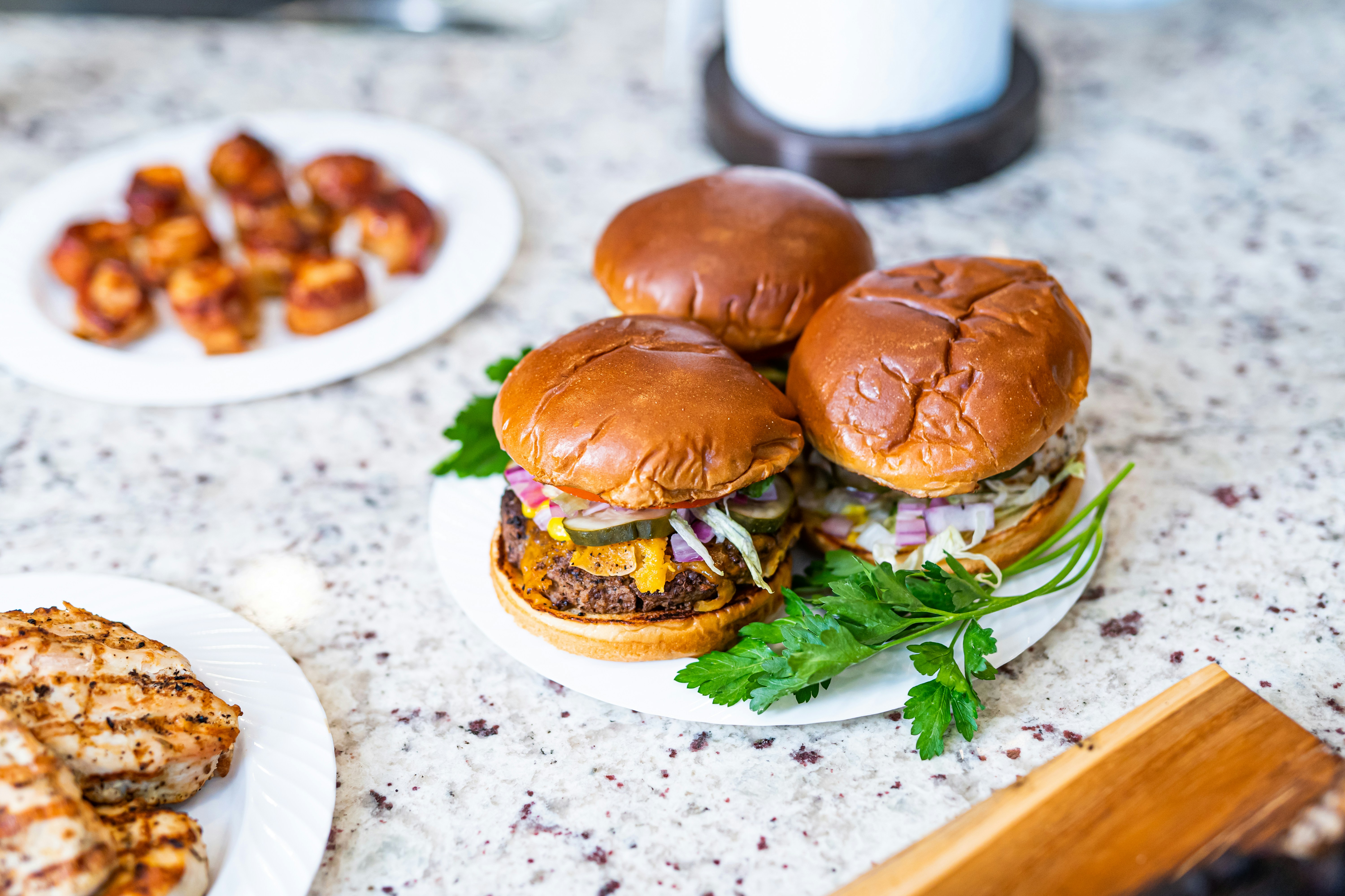 a couple of hamburgers on a plate next to a plate of food