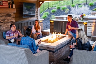 a group of people sitting around a table with a fire in it