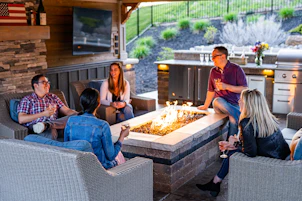 a group of people sitting around a table with a fire in it