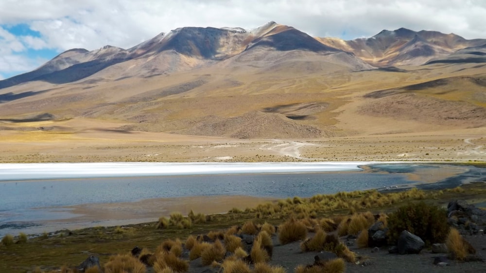 a desert landscape with a body of water and mountains in the background