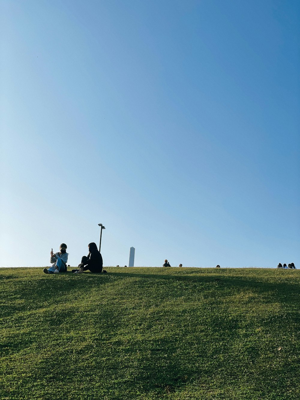 a group of people sitting on a grassy field