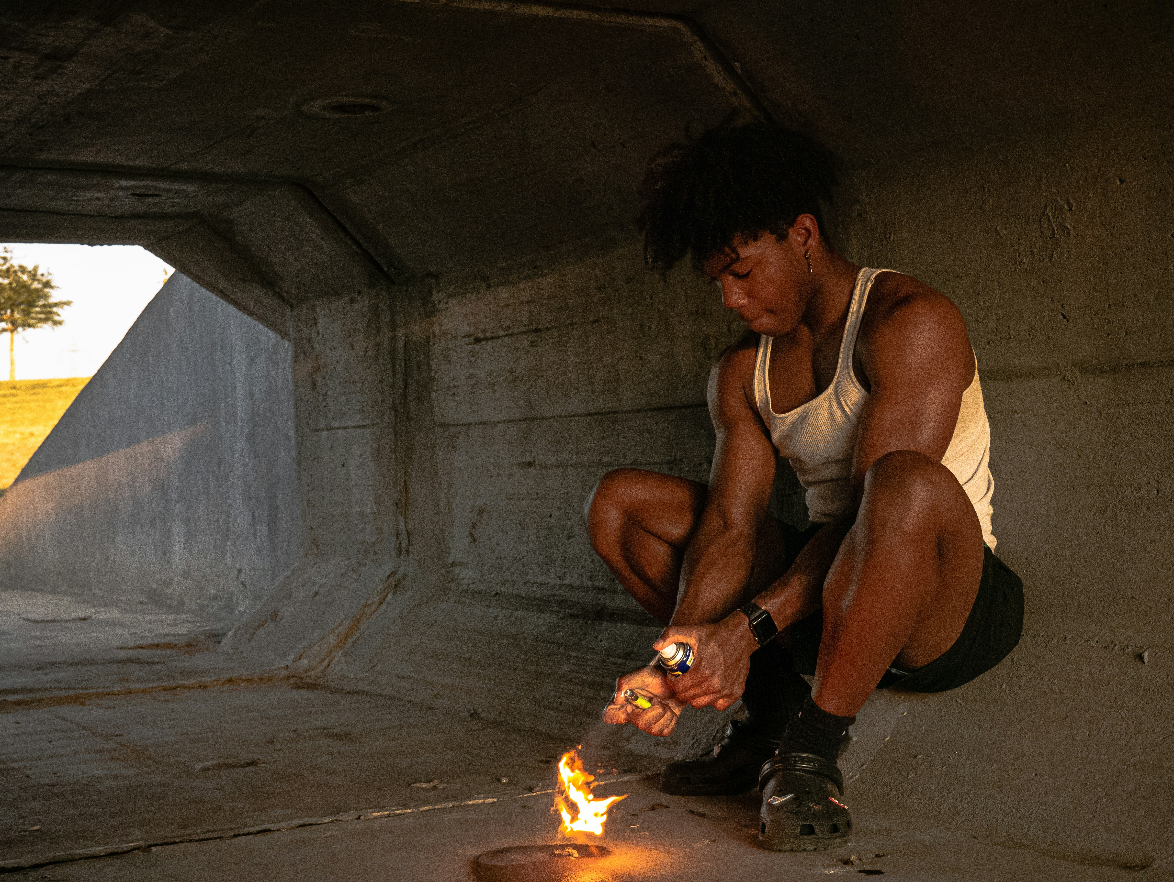 a person squatting next to a fire