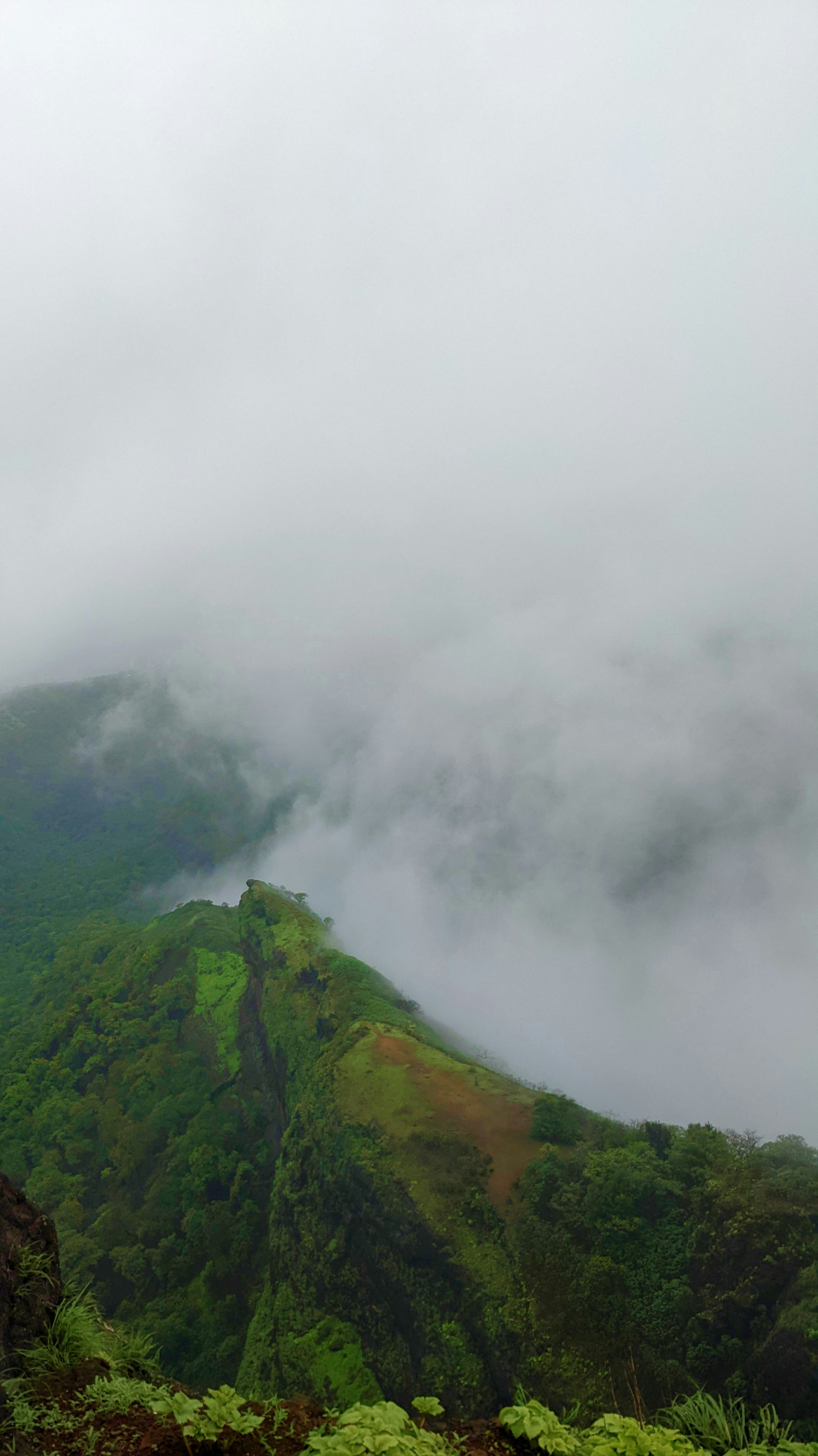 Misty mountain peaks with lush green valleys, dramatic clouds, bright morning light