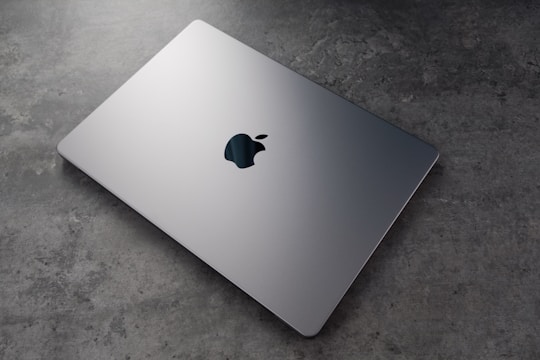 A sleek laptop displaying the web seller homepage with contact details.