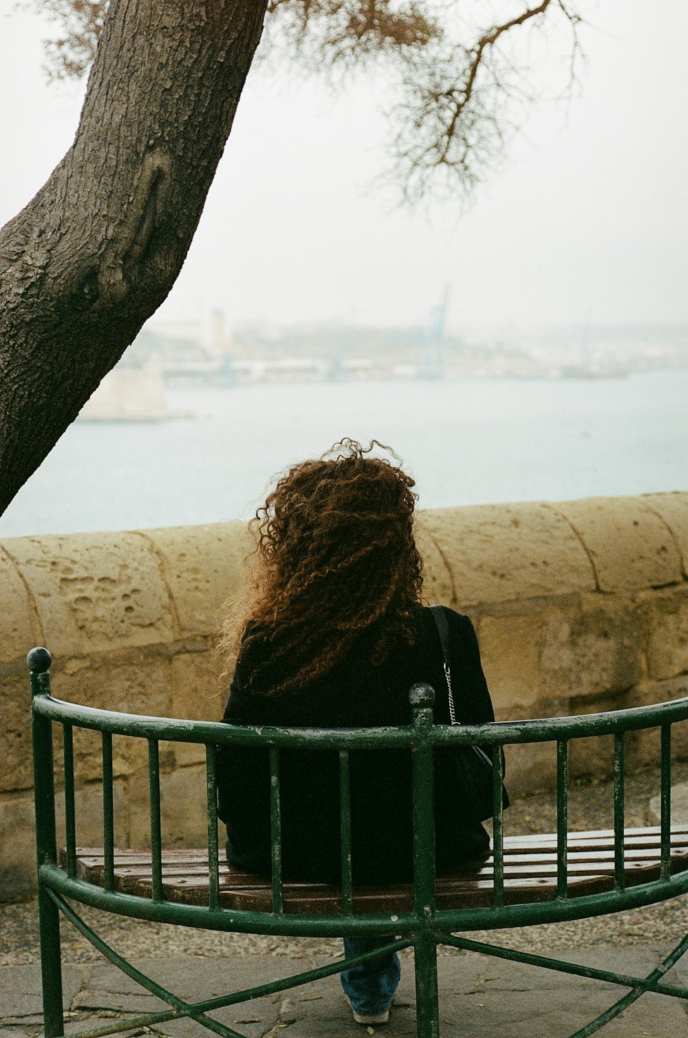 a person sitting on a bench looking out over a body of water