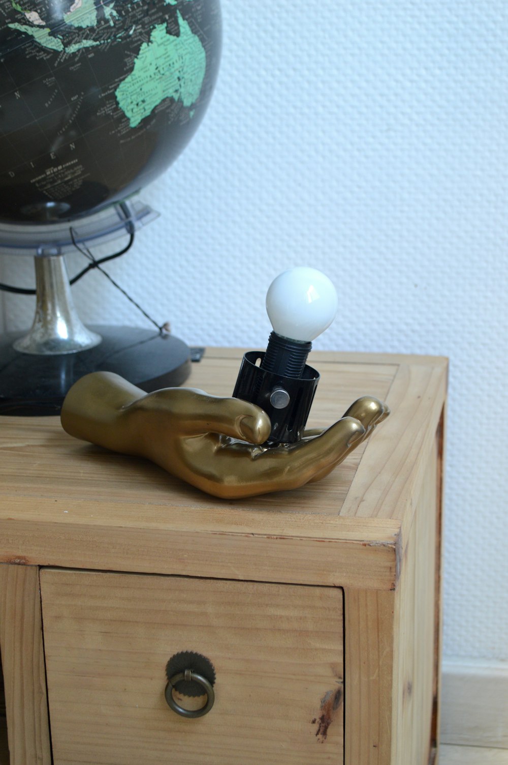 une commode en bois avec une lampe et un globe sur le dessus