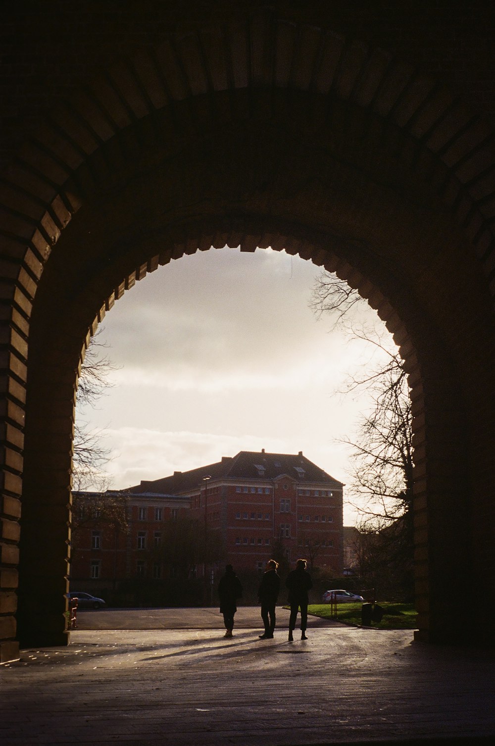 a group of people walking under a large arched archway
