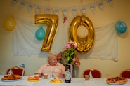 a person sitting at a table with food and balloons
