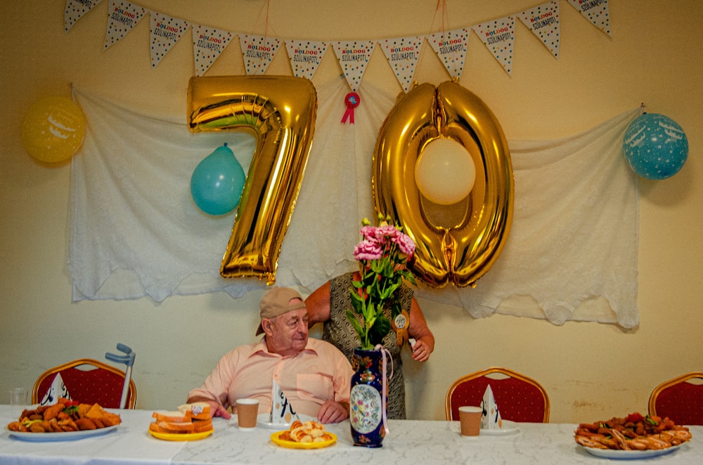 a person sitting at a table with food and balloons