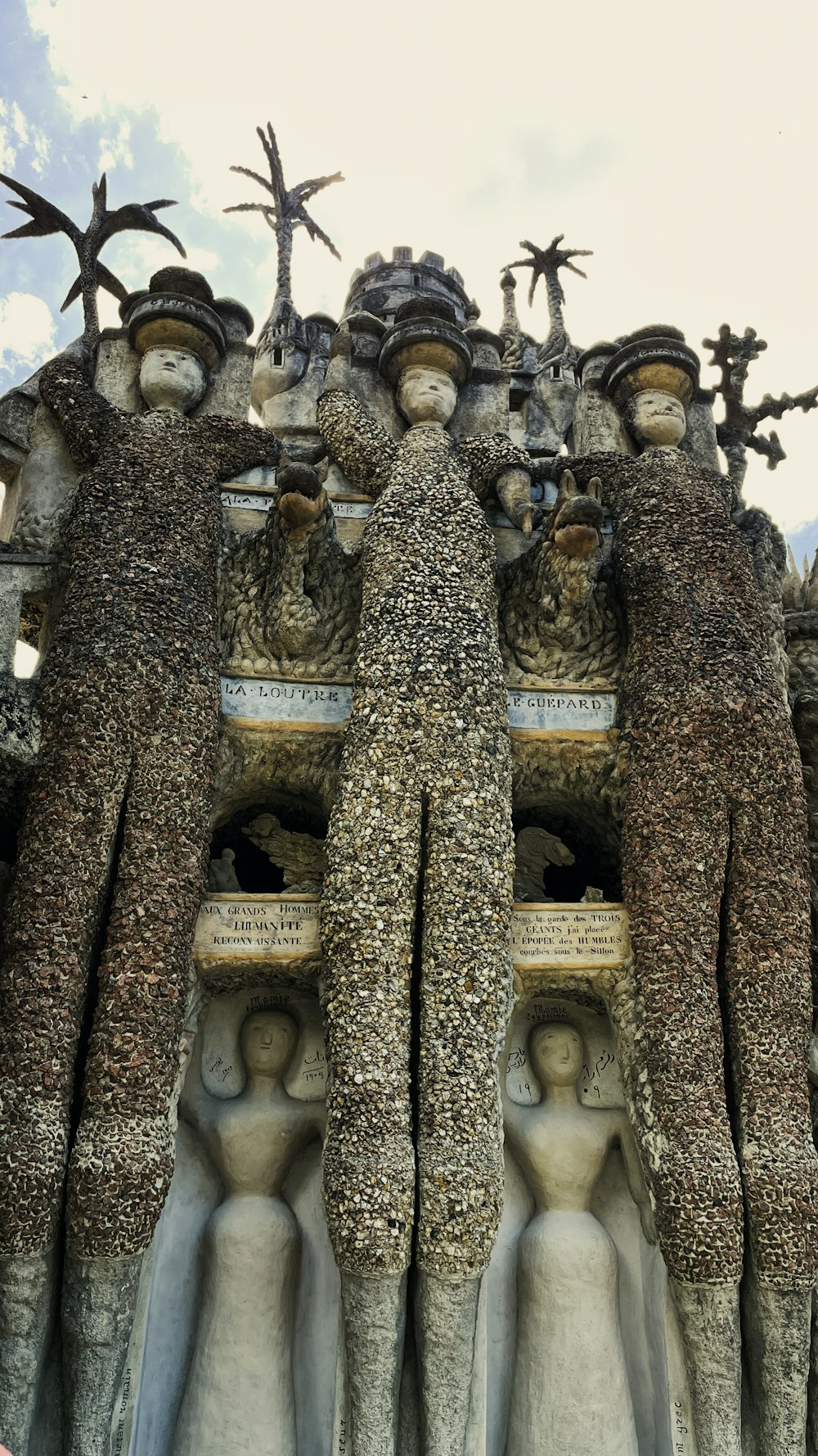 un grupo de estatuas con la Casa Batlló al fondo