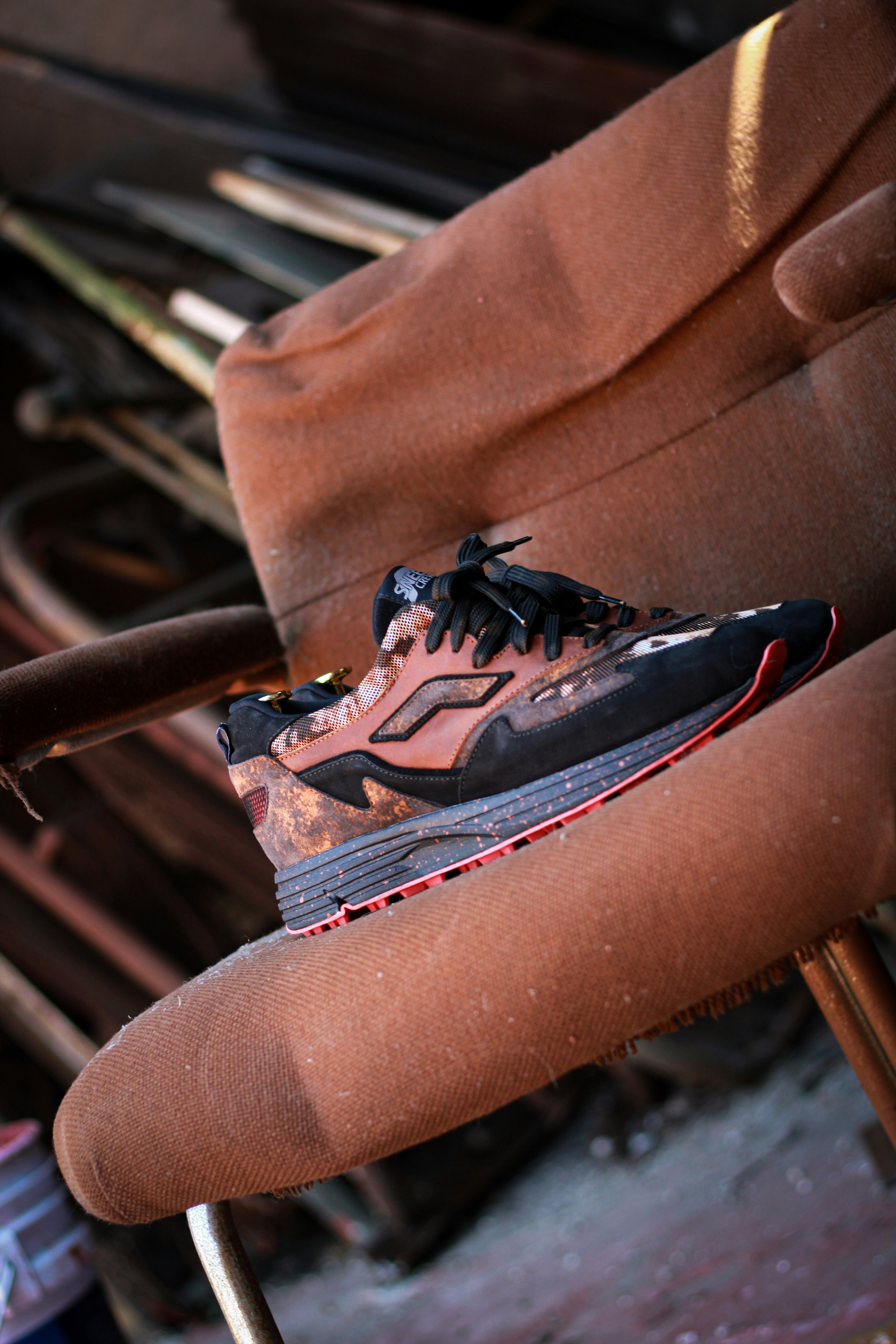 la main d’une personne tenant une chaussure noire et rouge