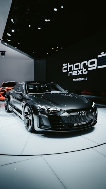 Sleek electric car accessories displayed on a minimalist black and metallic background with green and blue lighting accents