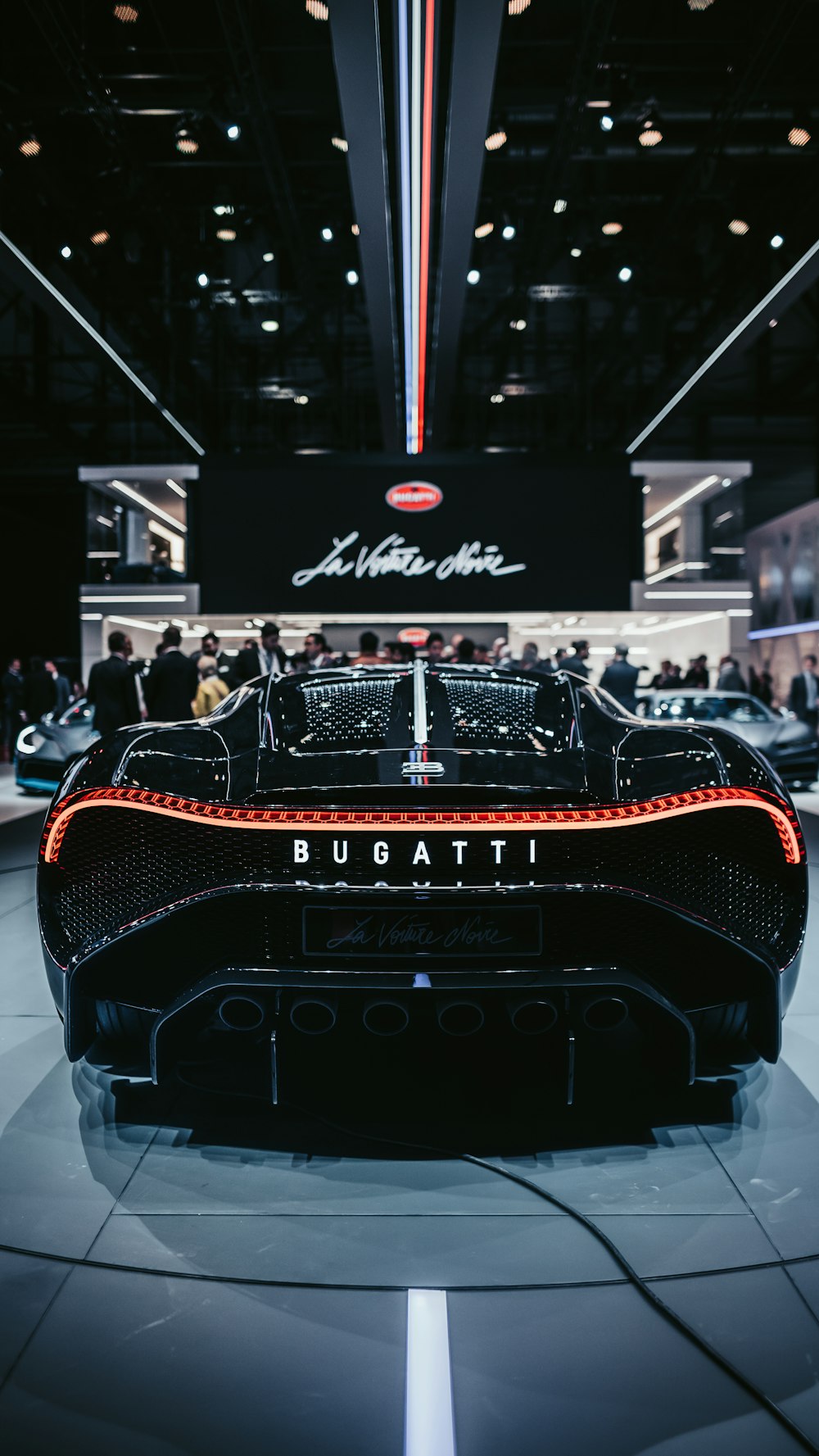 Ein schwarzer Sportwagen mit Menschen im Hintergrund