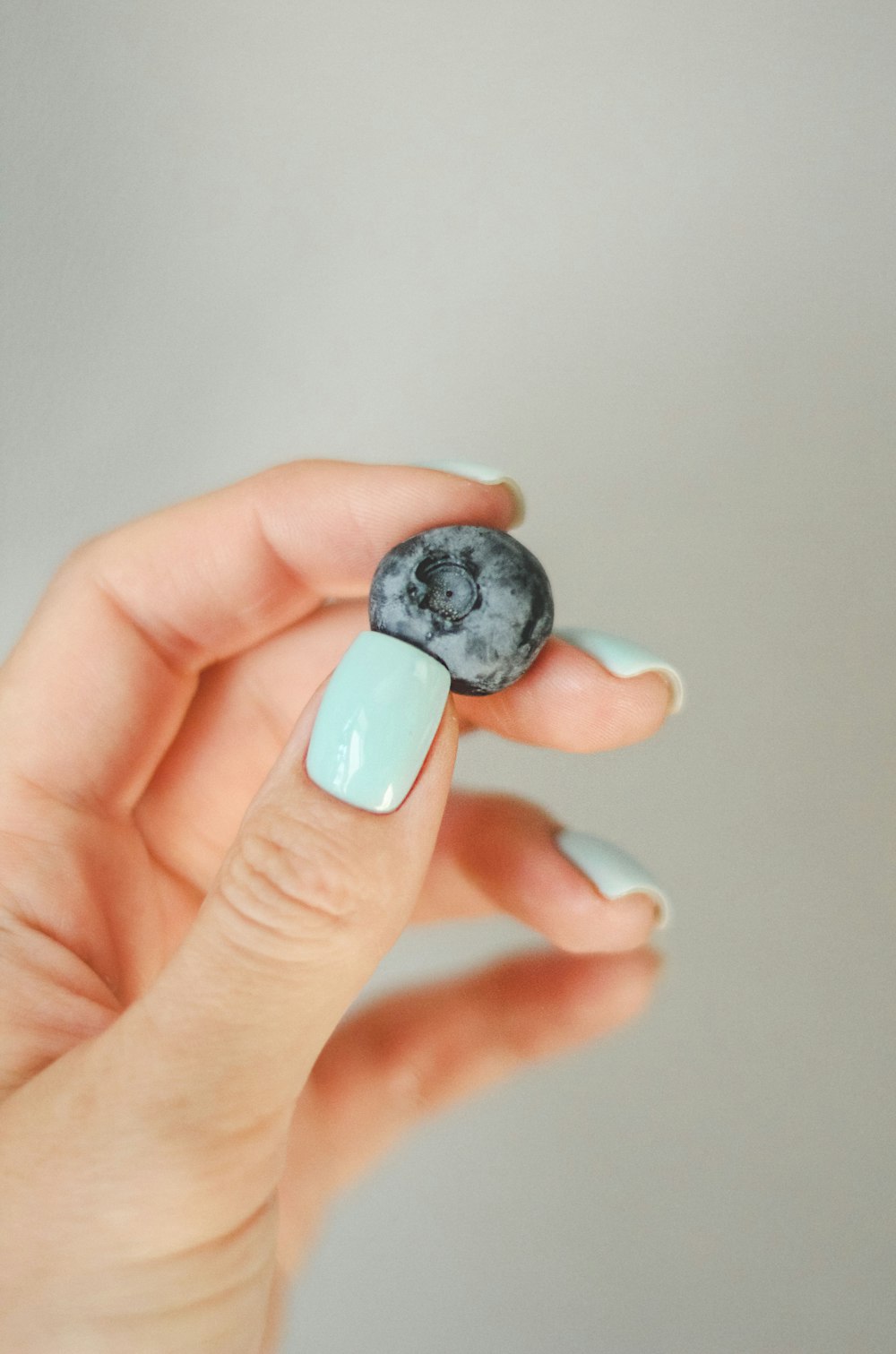 a hand holding a small blue and white object