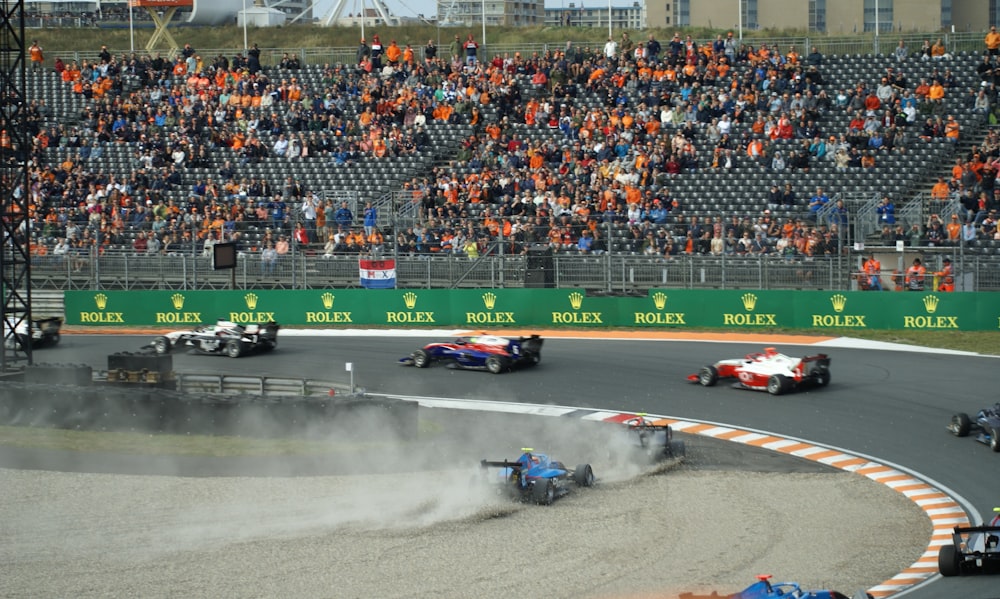 um grupo de carros de corrida em uma pista com uma multidão assistindo