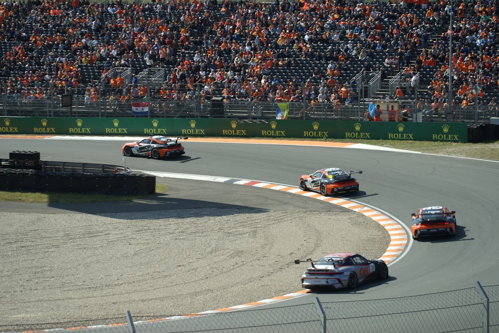 a group of race cars on a track with a crowd watching