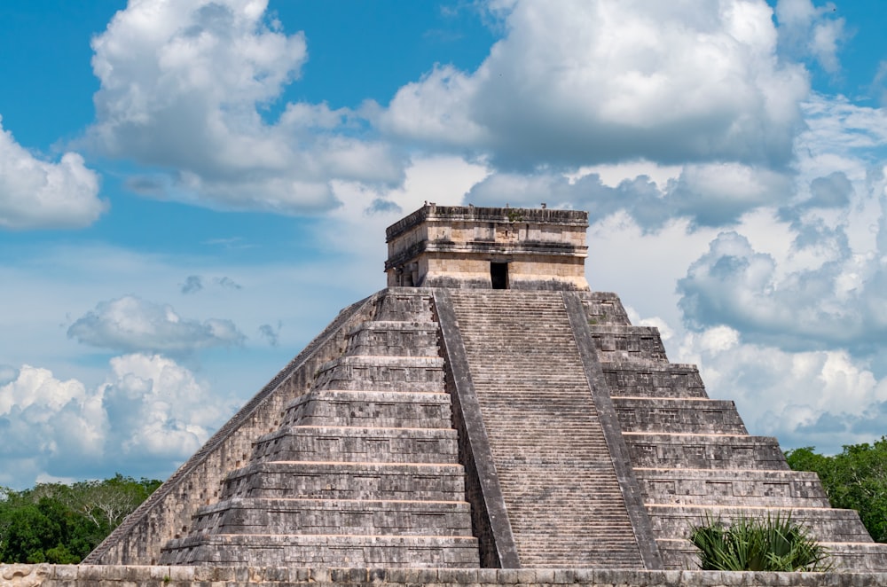 a large pyramid with a blue sky with Chichen Itza in the background
